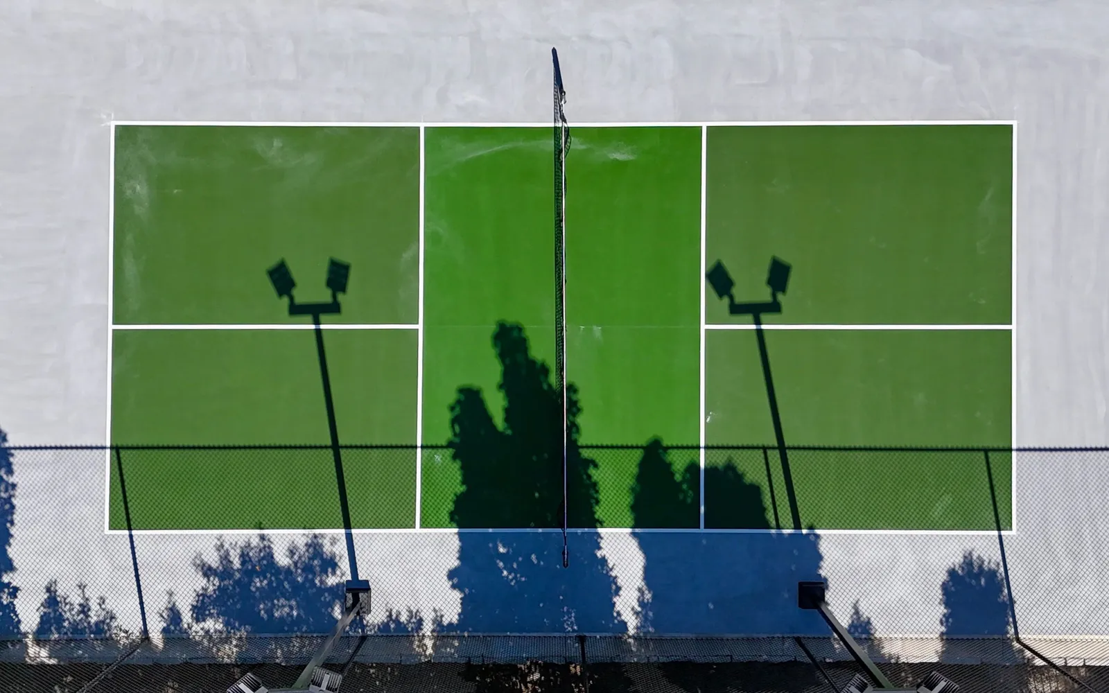 Aerial view of a pickleball court in two shades of green with a light gray surround