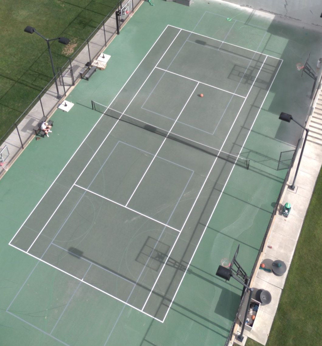 Faded tennis and pickleball court before resurfacing, aerial view